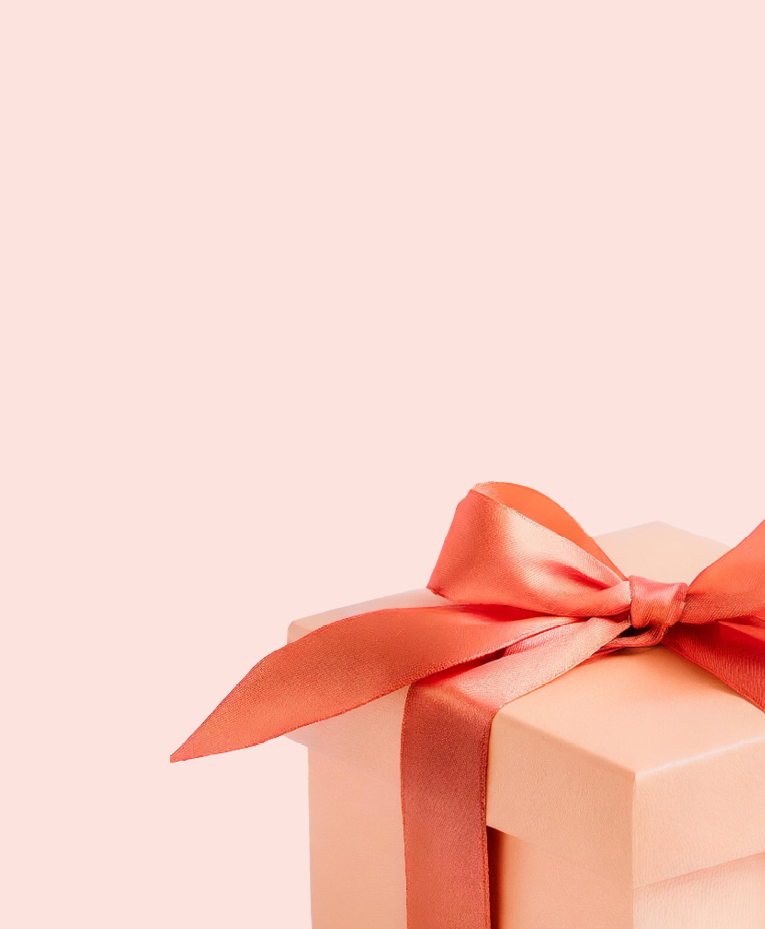 A peach-colored gift box with a shiny coral ribbon bow sits against a pale pink background. The box is partially shown in the lower right corner with ample empty space above.
