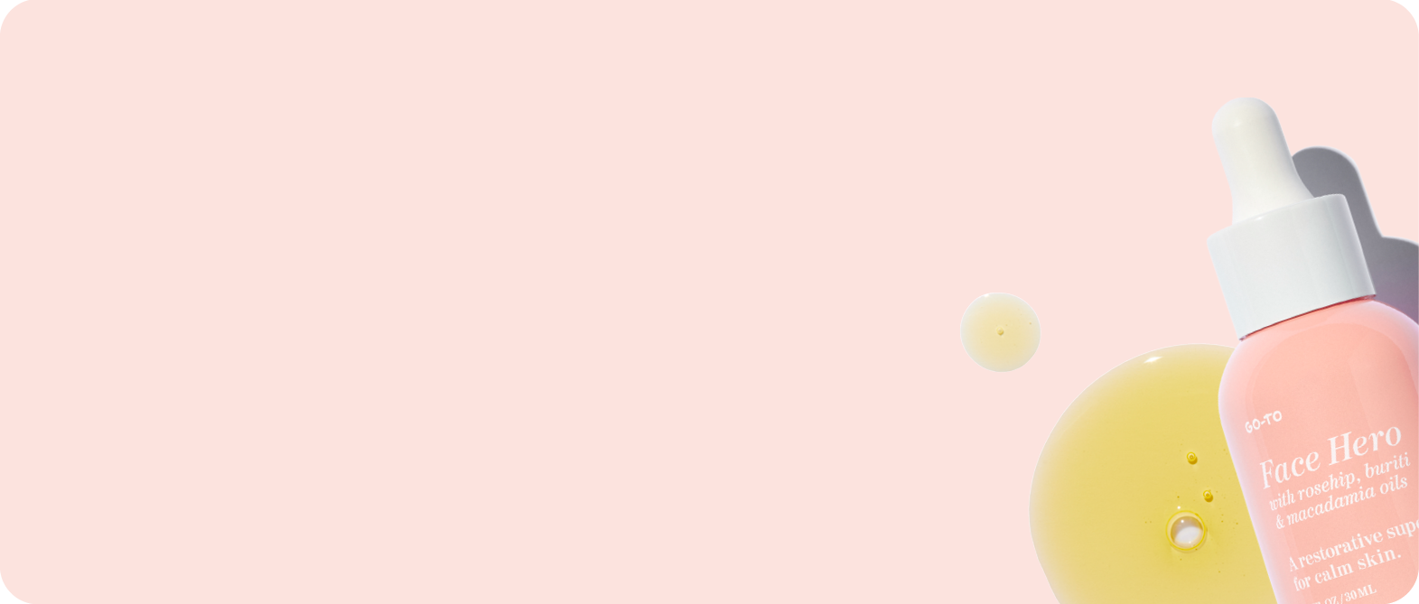 A pink bottle of skincare oil labeled Face Hero with a white dropper sits on a pale pink background, next to drops of yellow oil.