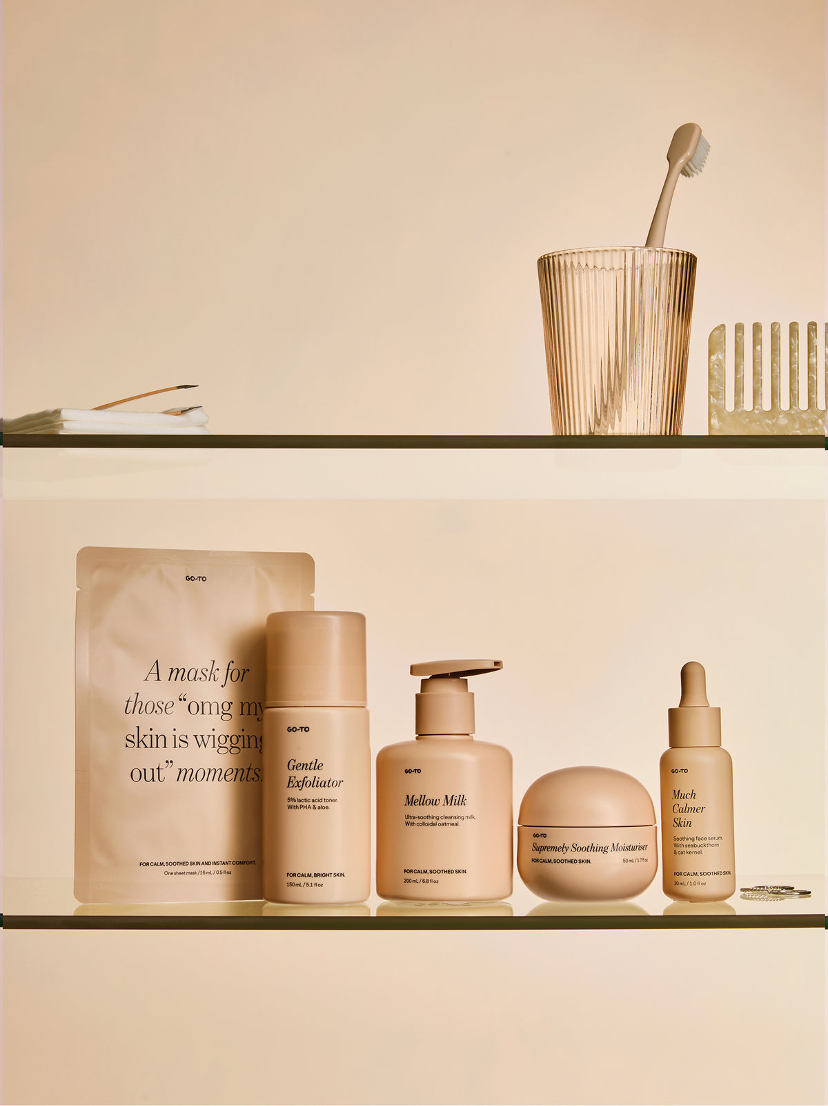 Go-To Skincare Gentle Exfoliator bottle displayed on a warm beige bathroom shelf with coordinating skincare products and a toothbrush in a glass holder